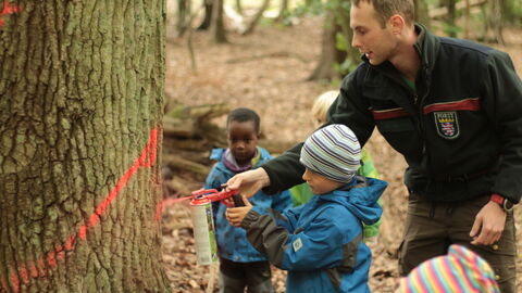 Waldpädagogik Förster mit Kindern beim Auszeichnen