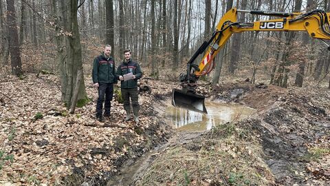 Es zeigt eine neu angelegte Sickermulde im Rodenbacher Staatswald. Links sehen Sie Revierförster Nils Koch und rechts den Funktionsförster Naturschutz Claus Keller, beide vom Forstamt Hanau-Wolfgang.