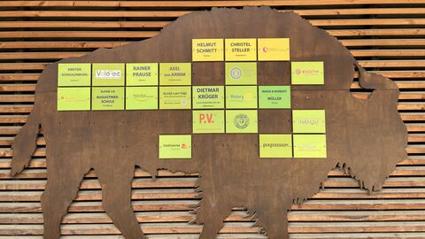 Spendenwisent Auf einem Wisent aus Holz sind die Logos der Spender angebracht