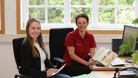 Ausbildung zur Verwaltungsfachangestellten bei HessenForst Eine ältere und eine jüngere Mitarbeiterin im Büro lächeln in die Kamera