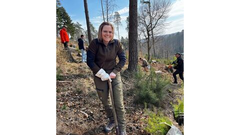 Eine Helferin zeigt wie man richtig pflanzt Eine Frau sticht mit einem Pflanzspaten ein Pflanzloch in die Erde