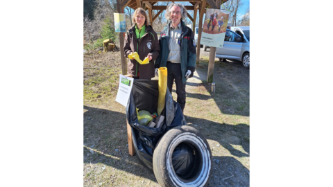 Auf dem Bild sehen sie eine Frau und einen Mann die vor einem großen Haufen Müll stehen. Darunter befindet sich sogar ein Autoreifen