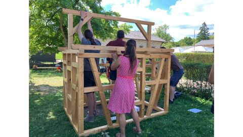Aufbau eines Fachwerkhauses durch eine Besuchergruppe Mehrere Personen bauen ein Miniaturfachwerkhaus auf