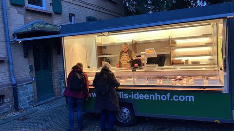 Zwei Menschen stehen in der Dämmerung vor einem erleuchteten verkaufswagen.