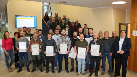 Die neuen Forstwirtschaftsmeister und Forstwirtschaftsmeisterinnen mit ihren Meisterbriefen. Daneben Das Team des Forstamtes mit Dr. Hendrik Horn. Im Hintergrund Staatssekretär Köfer. 