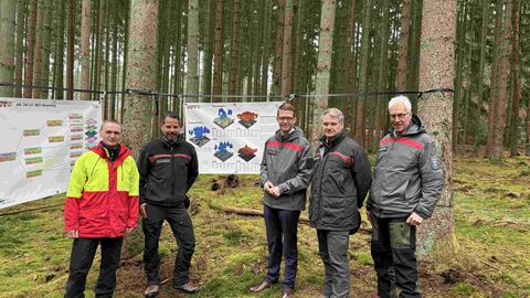 Fünf Männer stehen in einem Fichtenbestand vor zwie aufgespannten Bannern mit wissenschaftlichem Inhalt zum Modellbetrieb Klimaschutz PLUS.. 