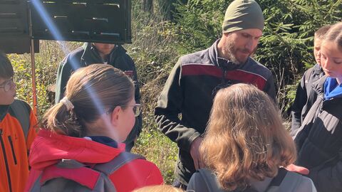 Ein Förster steh mit kindern an einer Pheromonfale und erklärt. 
